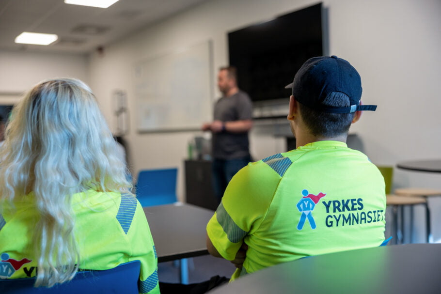Två elever på Yrkesgymnasiet sitter i klassrummet och lyssnar på läraren.