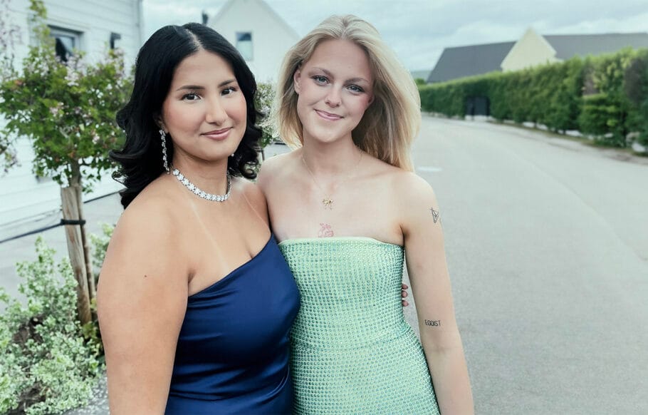 En bild på eleverna Maja och Shila på deras studentdag. De har på sig sina studentklänningar och ler mot kameran.