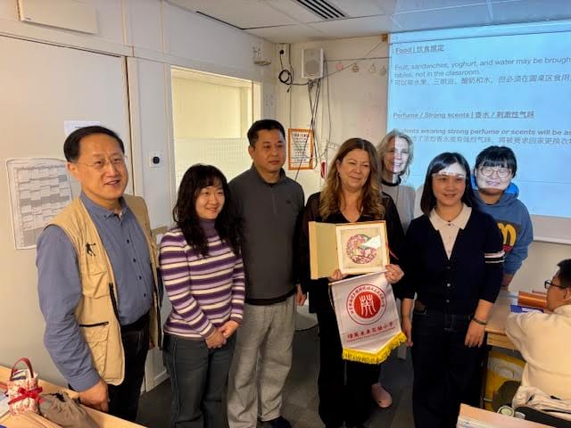 Foto på besökare och värdar framför en whiteboard.