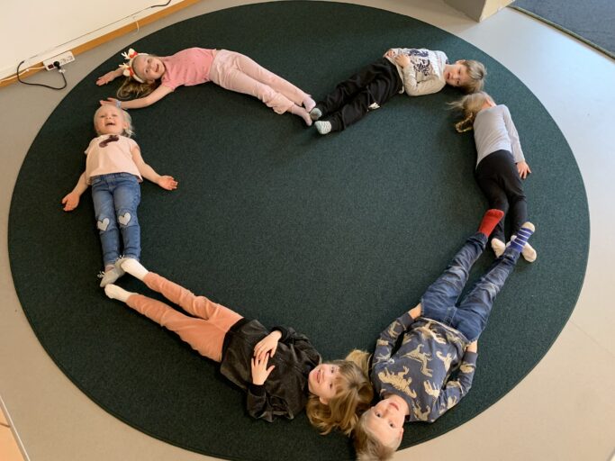 Foto på barn som formar ett hjärta på en matta.