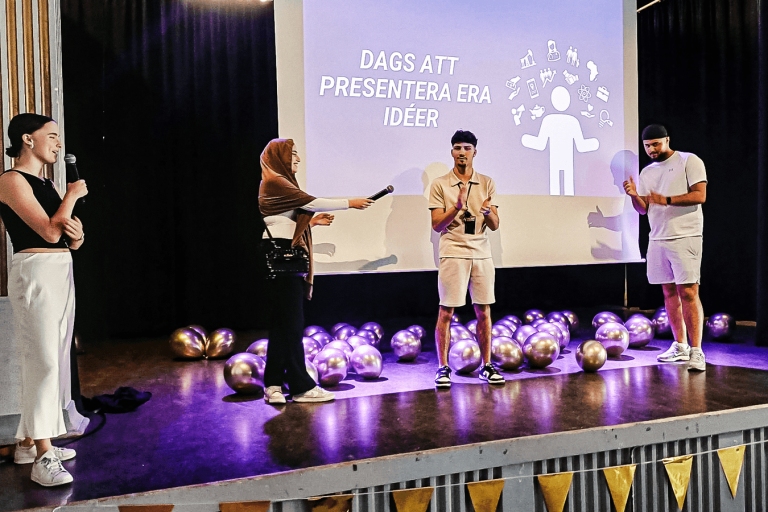Fyra elever på Affärsgymnasiet Malmö står på en scen och pratar.