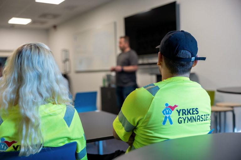 Två elever på Yrkesgymnasiet sitter i klassrummet och lyssnar på läraren.