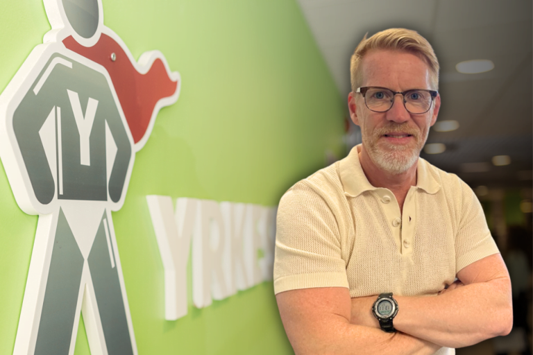 Rektor Martin Hultman står med armarna i kors och ler framför en limegrön vägg med Yrkesgymnasiet logotyp på.