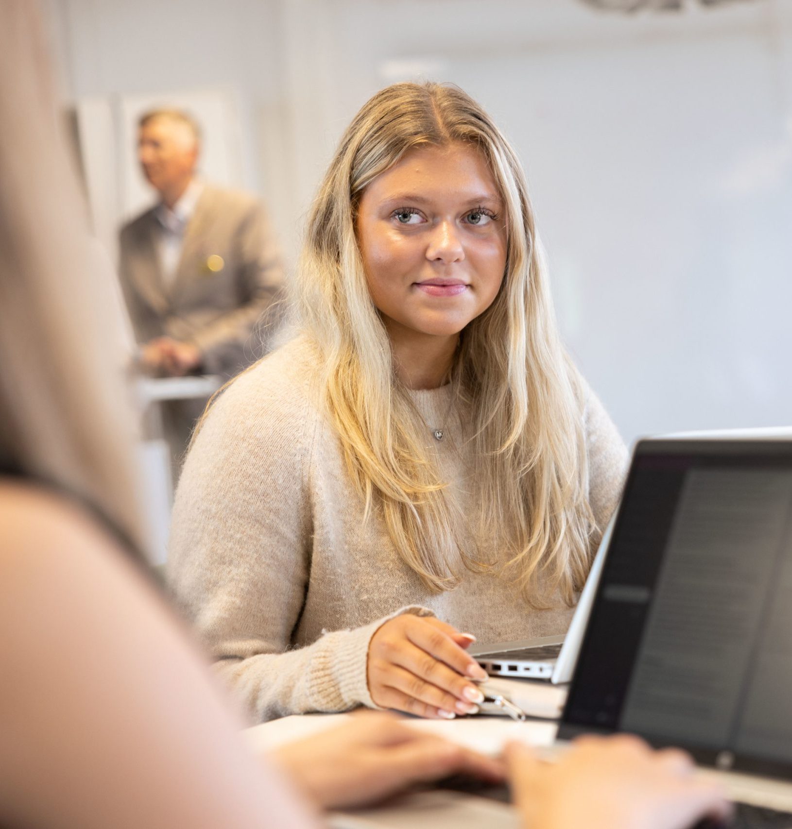 Gymnasieelev sitter vid laptop i klassrum.