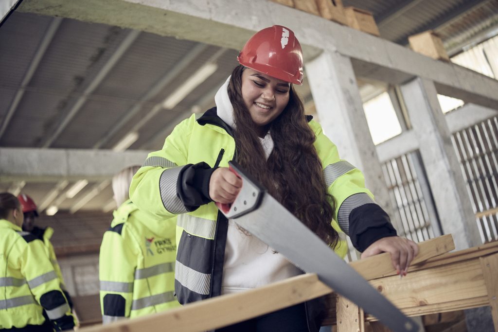 Student i skyddsutrustning som arbetar praktiskt inom byggmiljö.