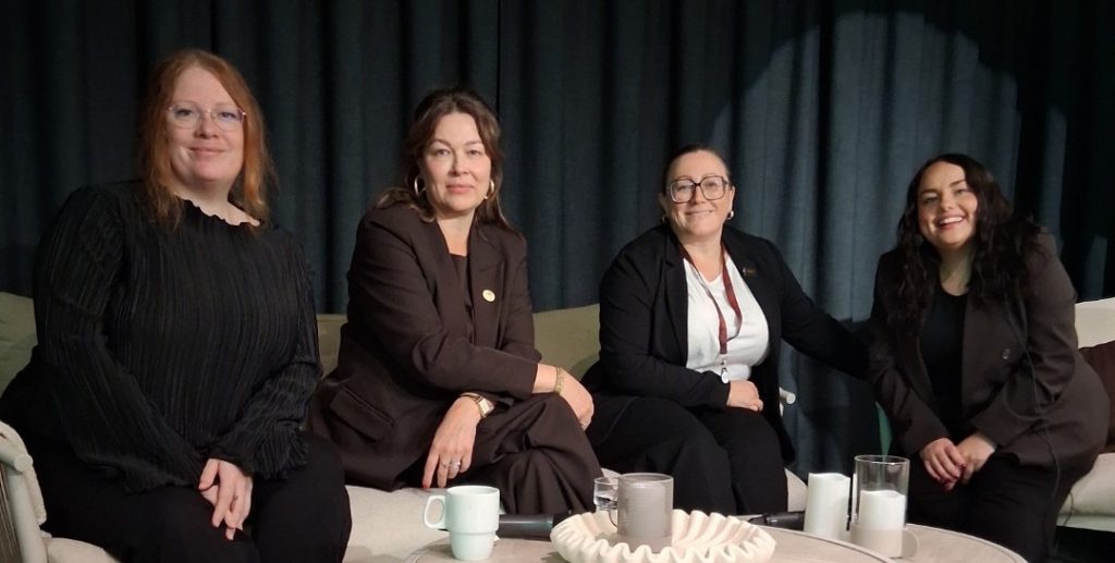 Foto på fyra kvinnor som sitter i rad på en soffa.